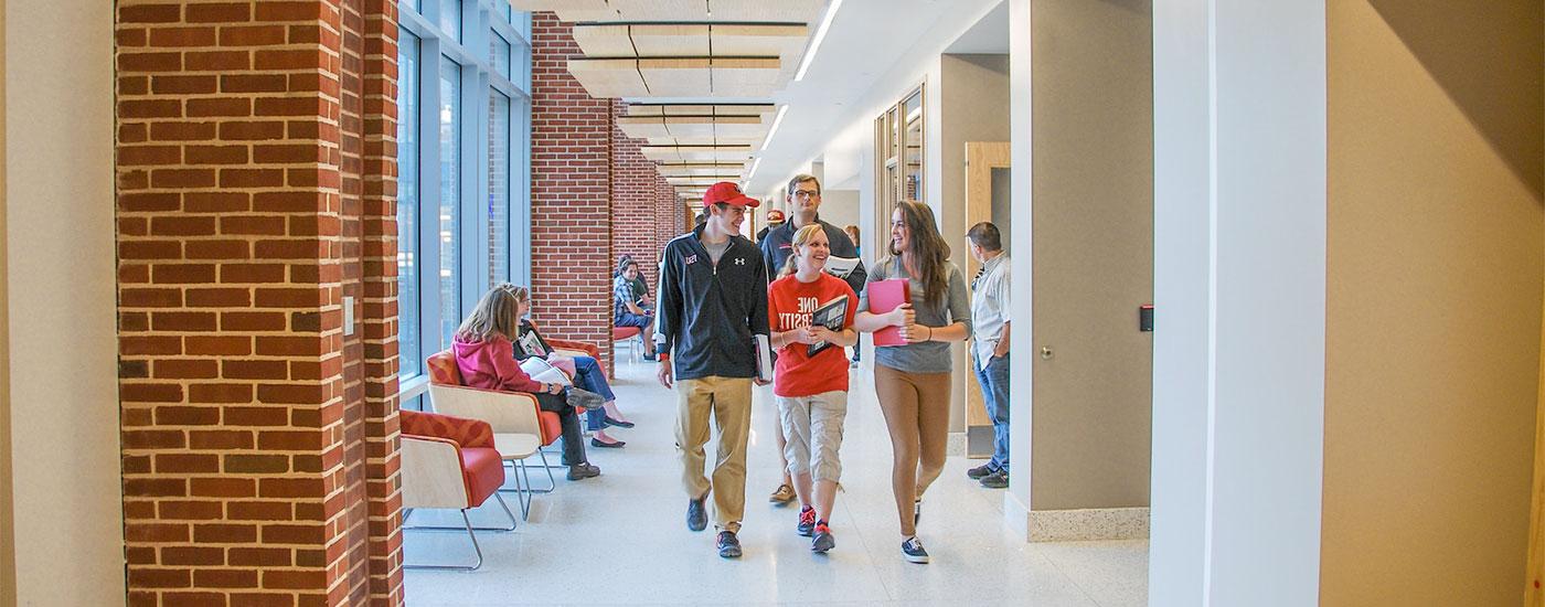 Students walk down a hallway and laugh in between classes