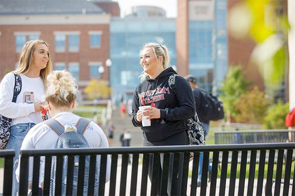 3 girls chatting outside of the Gira Center while sitting on a park bench