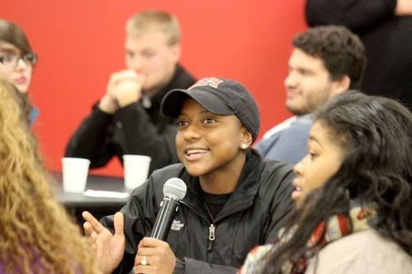 A female student talks into a microphone during a group discussion