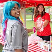 A student volunteer handing out popcorn at a carnival